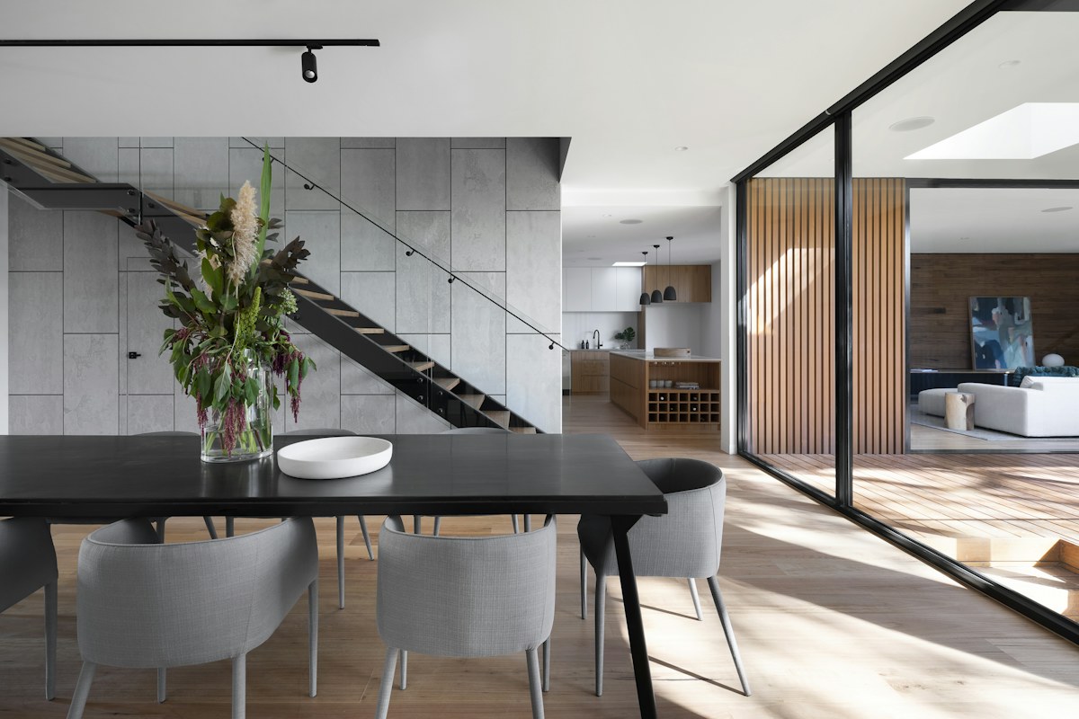 Minimal dining room with a dark table, stone finishes, and timber details.